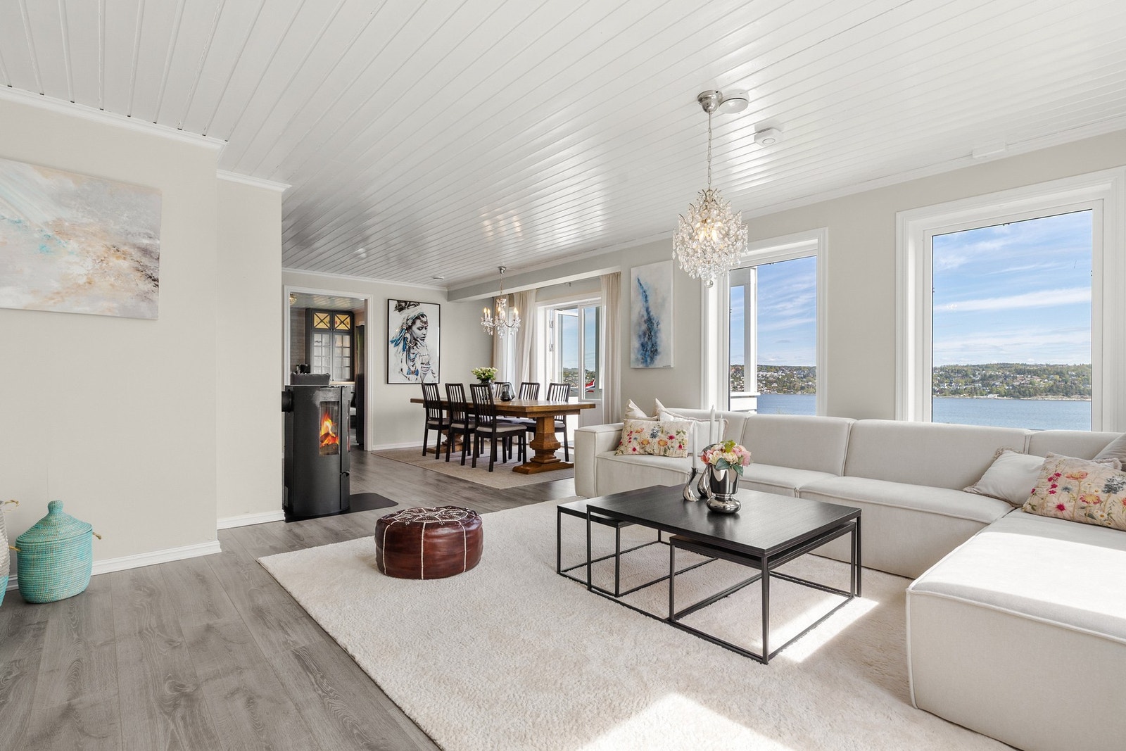 Dagslyset strømmer inn via store stuevinduer, og lyset gjenspeiles fint i de lyse overflatene. Galleribilde