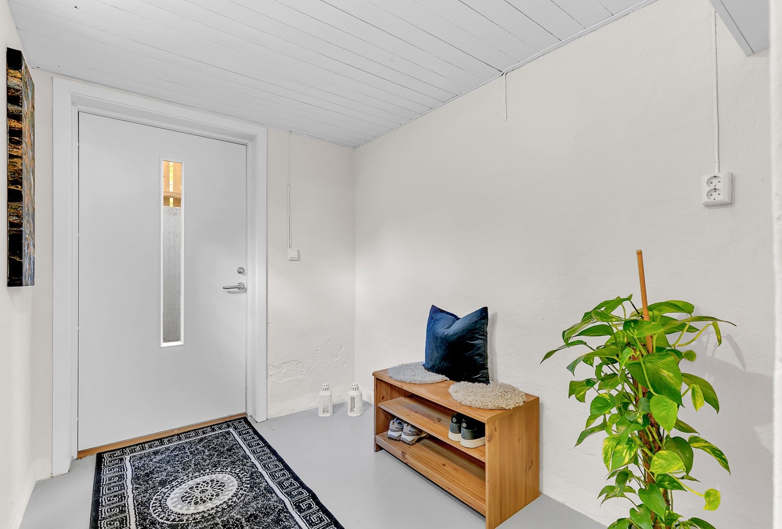 Egen inngang (etablert i 2023) fra østsiden av huset med trapp ned. Ny inngangsdør med glassfelt. Alle overflater er malt. Her er det god plass til garderobeskap langs hele sydveggen. Galleribilde