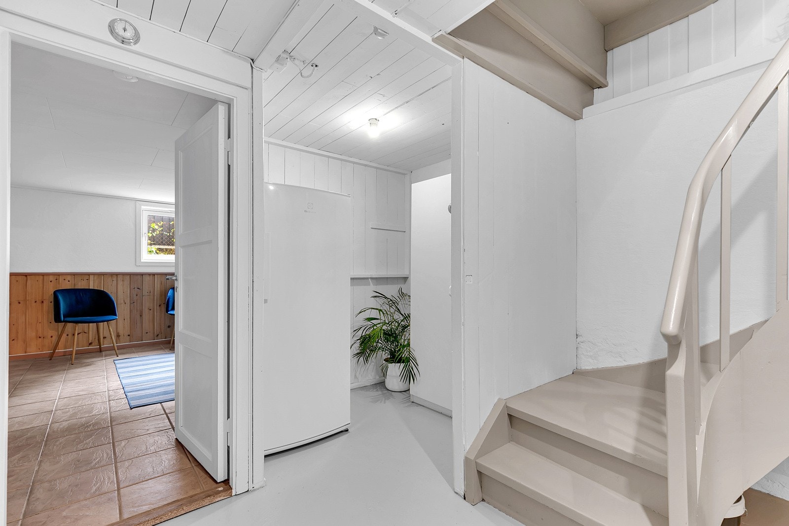 Et luftig trapperom i kjelleretasjen med egen nisje for skap og ekstra fryser/kjøleskap. Galleribilde