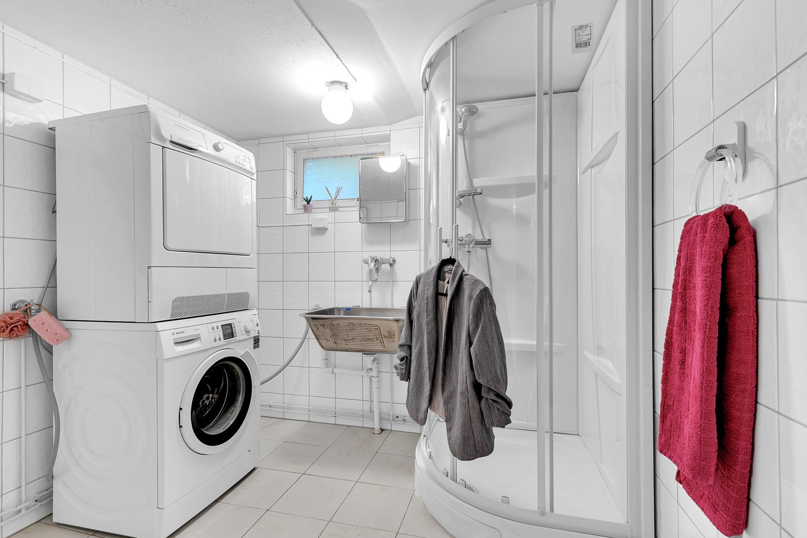 Bad/vaskerom med flislagte flater og varmekabler i gulv. Gulvstående toalett og dusjkabinett. Utslagsvask av stål. Det er opplegg for vaskemaskin og tørketrommel. Galleribilde