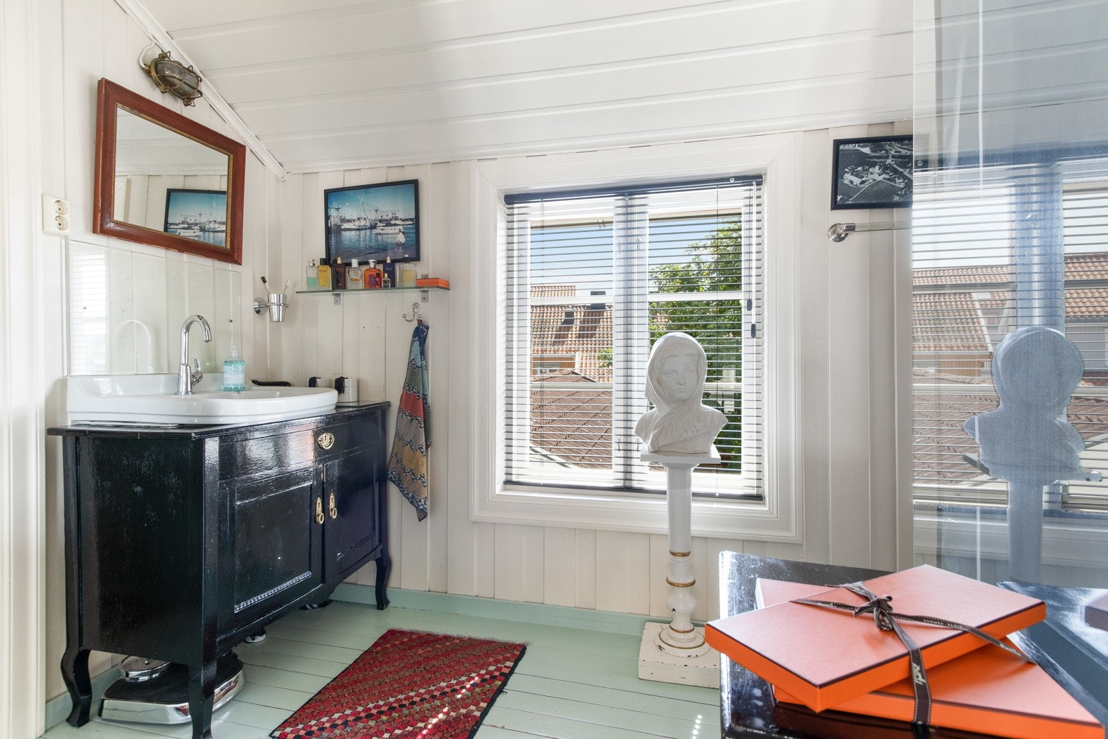 Innredningen på badet består av en nedfelt servant i en sort skapseksjon, og rommet har videre et dusjhjørne med regnfallsdusj. Galleribilde