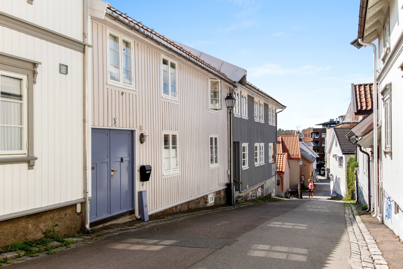 Eneboligen har et sjarmerende og tidstypisk inngangsparti rett fra gaten med en blåmalt, tofløyet ytterdør og veggmontert utebelysning. Galleribilde