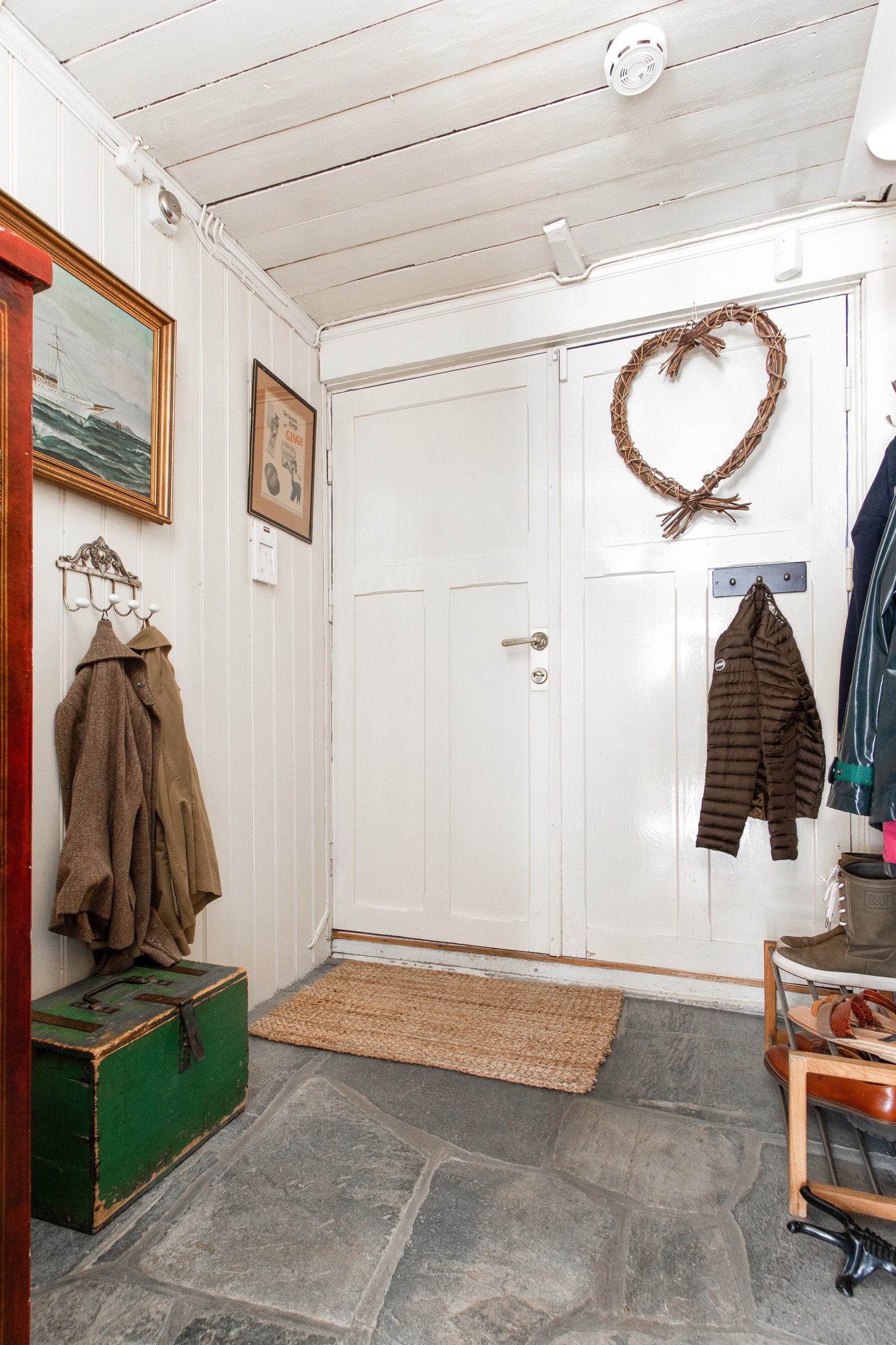 Bak den blå inngangsdøren kommer vi inn i en koselig entré med skiferbelagt gulv, blåmalte murvegger og hvitmalte tømmervegger. Galleribilde
