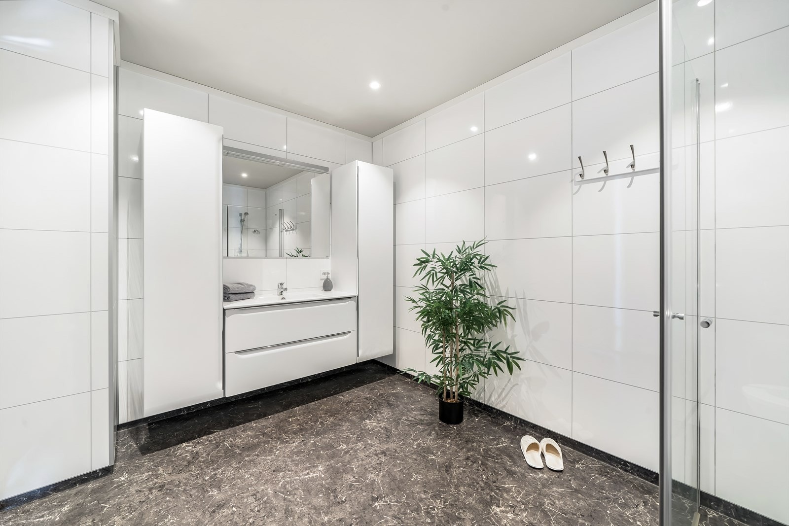 Lyst og tidløst bad med belegg på gulv og baderomsplater på vegg. Rommet er innredet med baderomsinnredning, toalett og dusjløsning. Varmekabler i gulv. Galleribilde