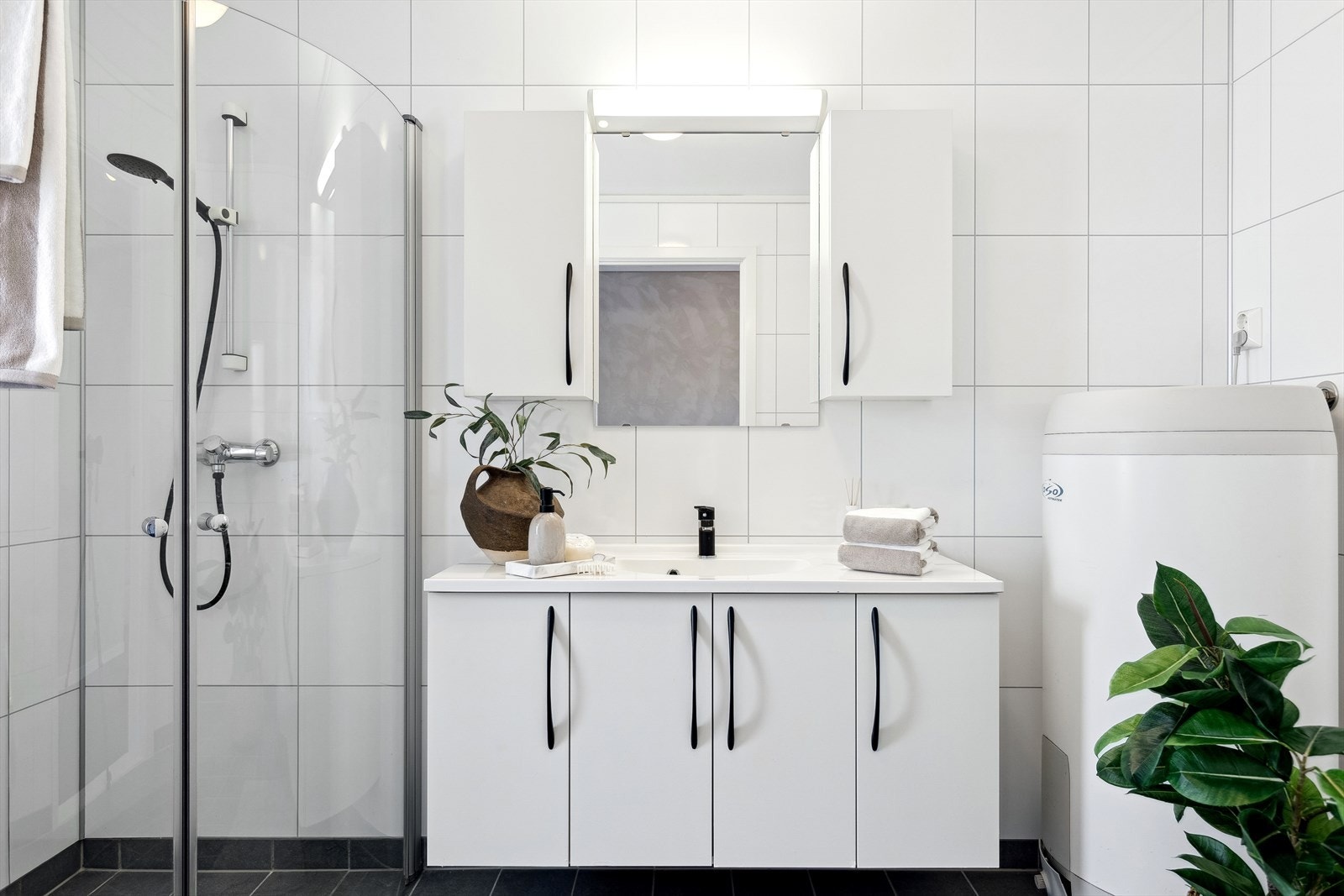 Innredning med heldekkende servant, overskap m/speil og belysning, dusjhjørne, toalett, varmtvannsbereder og opplegg for vaskemaskin. Galleribilde