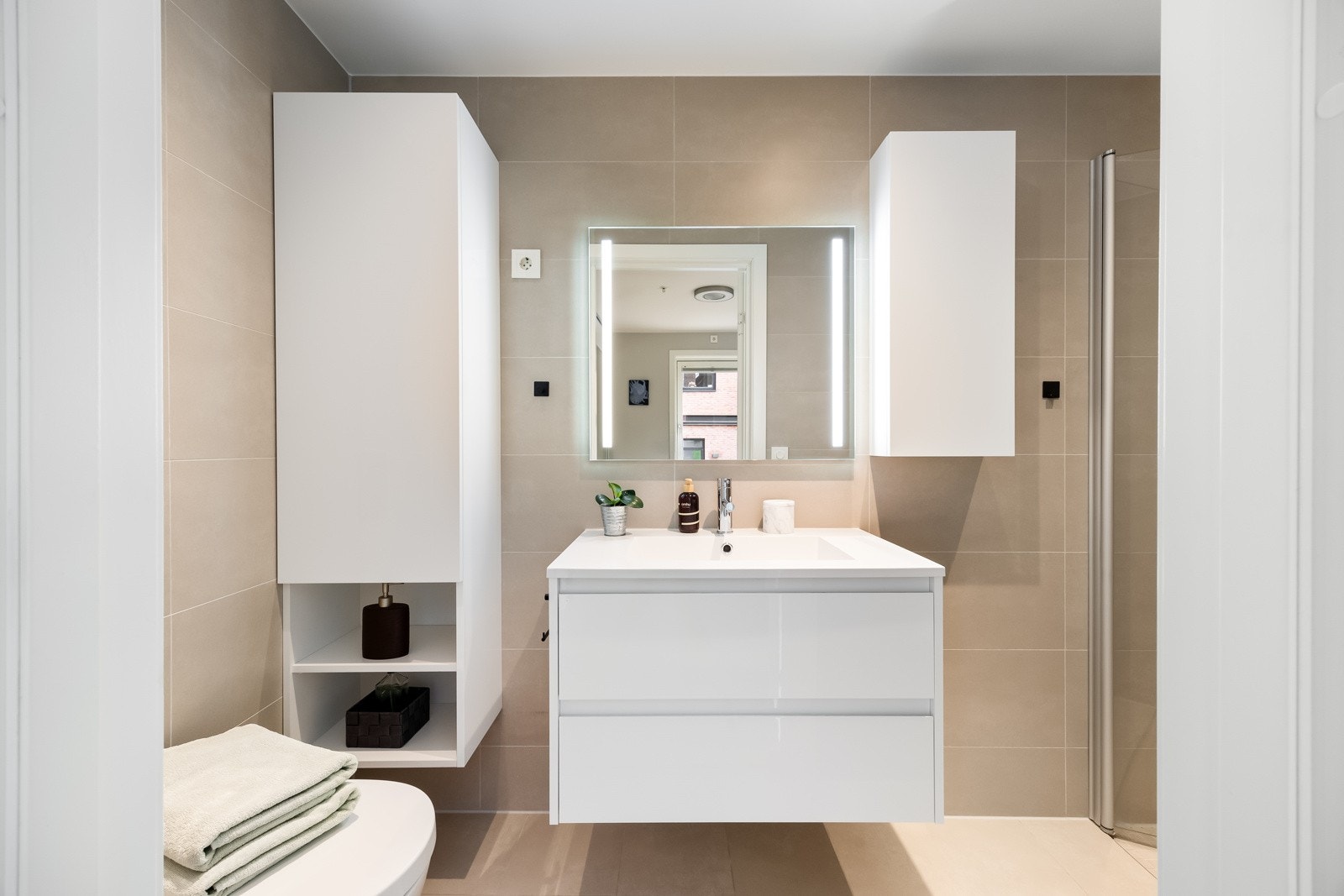 Badet har et lekkert og stilfullt preg med fliser på både vegger og gulv, downlights og varmekabler. Galleribilde