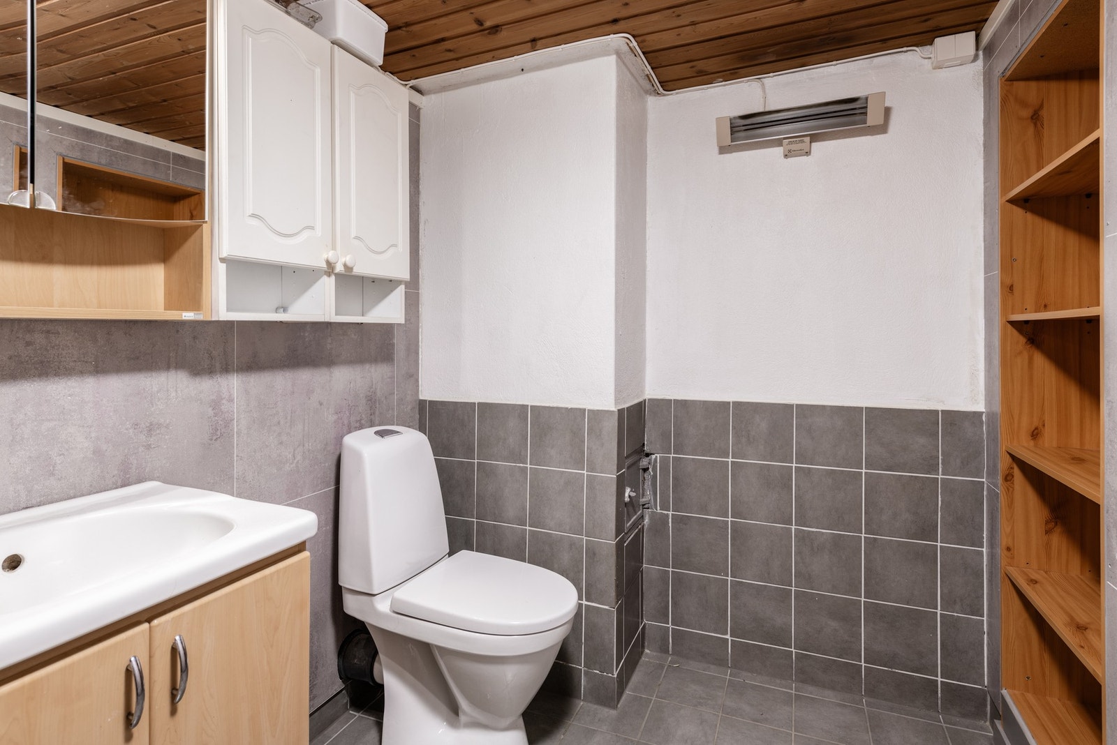 Badet er innredet med toalett, baderomsinnredning, dusj og plassbygd hyller i vegg. Galleribilde