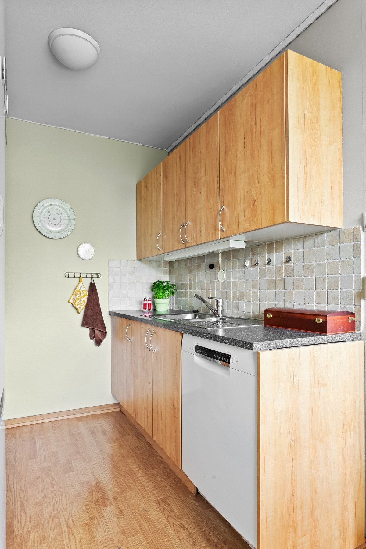 Eldre kjøkkeninnredning med glatte fronter, og benkeplate i laminat med nedfelt kum i rustfritt stål. Galleribilde