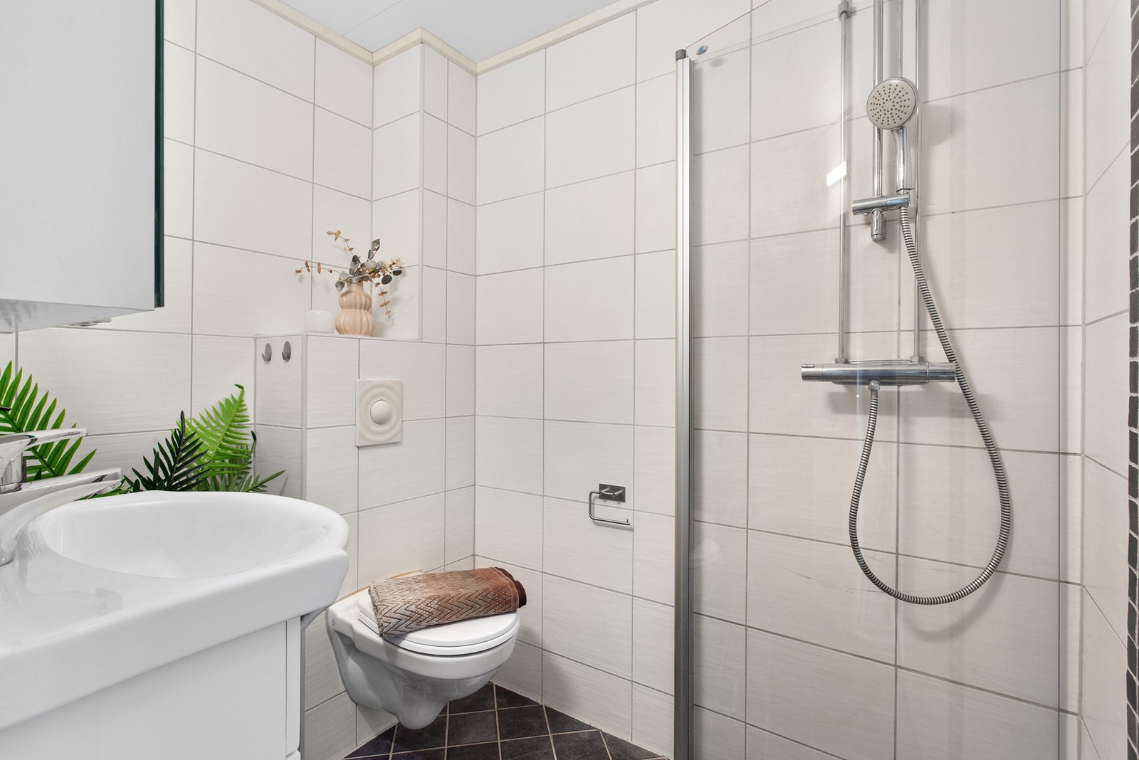 Badet har et vegghengt toalett, dusjhjørne med svingdør i glass og opplegg for vaskemaskin. Galleribilde