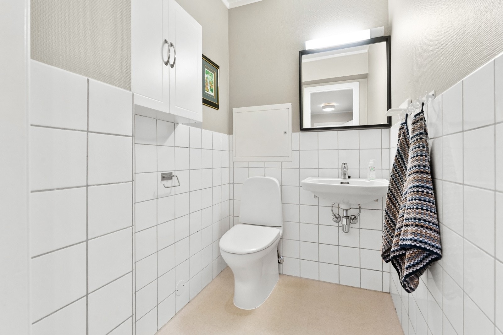 Separat toalettrom med gulvmontert toalett, vegghengt servant og speil. Galleribilde