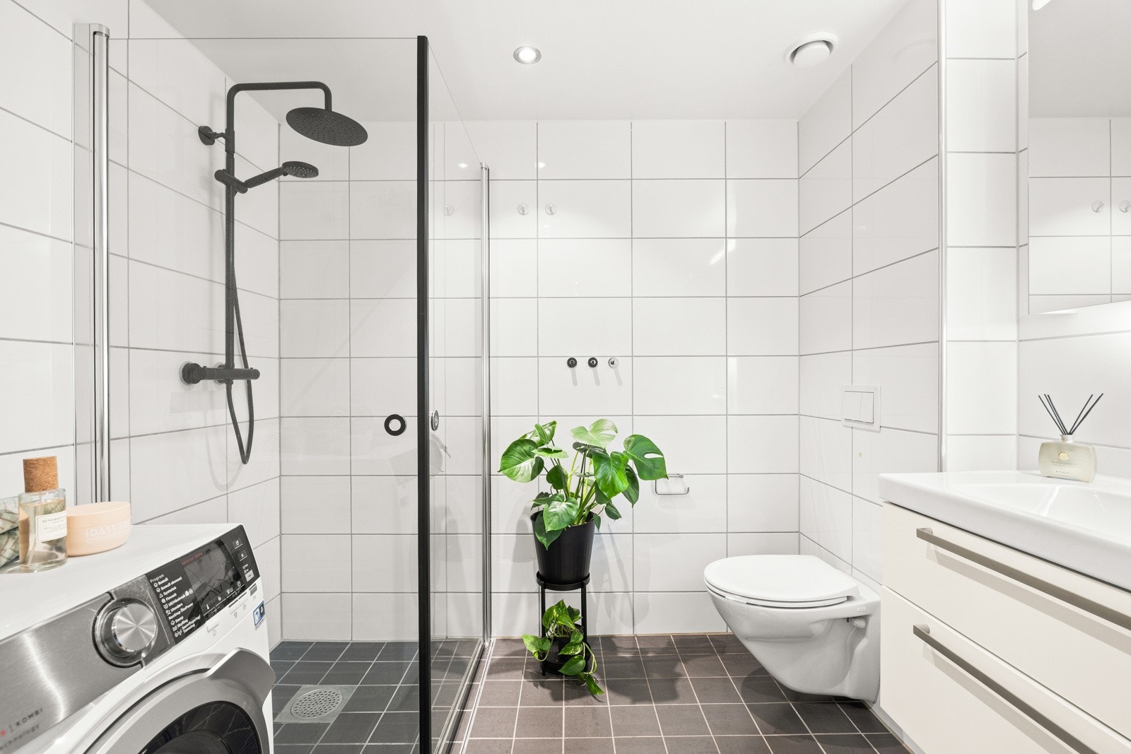 Det flislagte badet er av god størrelse og er innredet med servantmøbel med skap, speilskap med lys, veggmontert toalett med TECE-sisterne/safetybag, dusjnisje og opplegg til vaskemaskin. Galleribilde