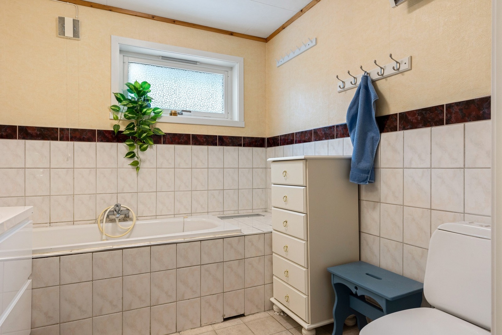 Baderommet i hovedetasjen er innredet med servant med underskuffer, toalett og badekar Galleribilde