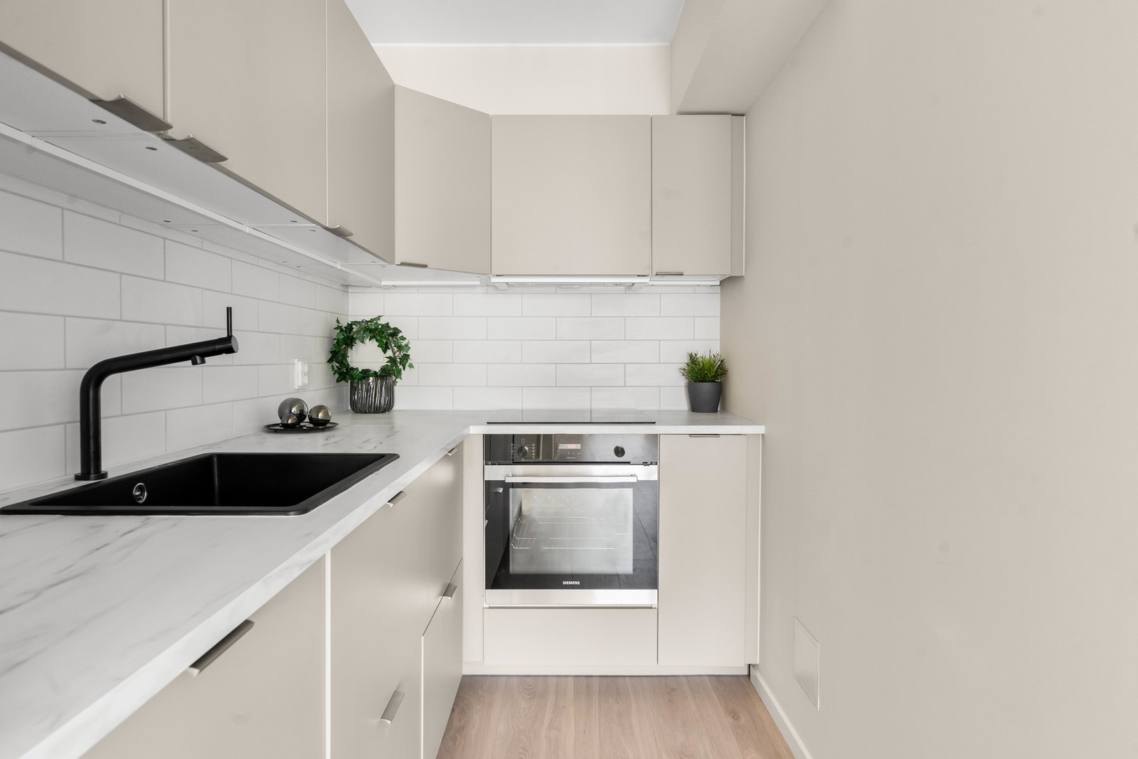 Kjøkkenet fremstår moderne med lyse overflater og integrerte hvitevarer. Galleribilde