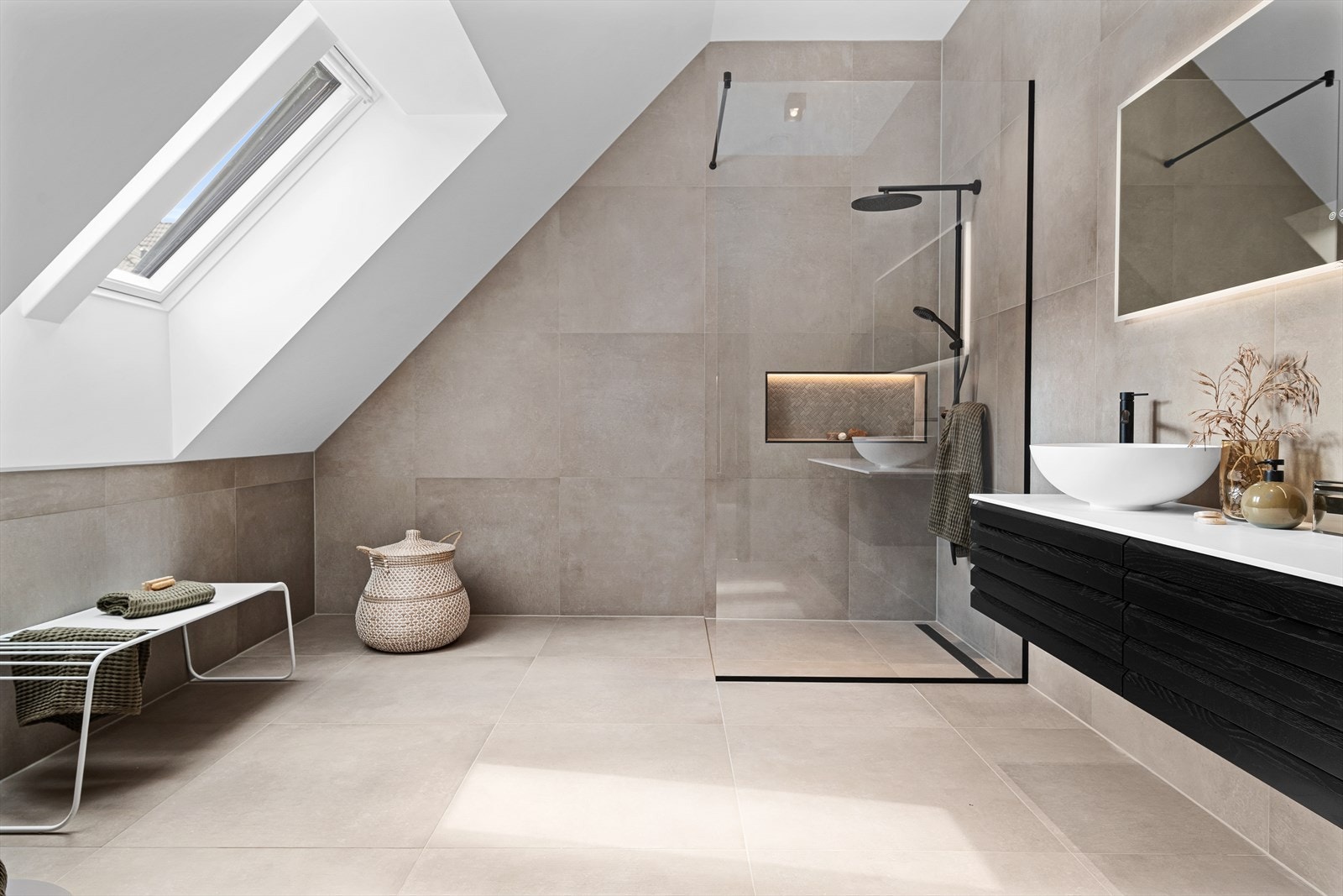 Baderommet er dekorativt innredet med flislagte overflater og stilren baderomsinnredning. Lekre detaljer som fiskebensfliser av mosaikk i stedsbygd dusjhylle. Galleribilde