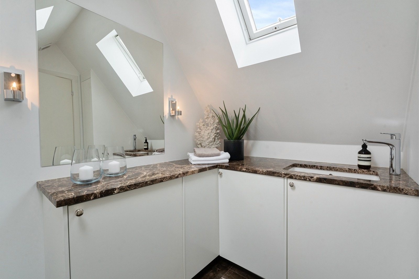 Lekkert vaskerom/gjeste-wc med benkeplater i marmor og plassbygget innredning. Galleribilde