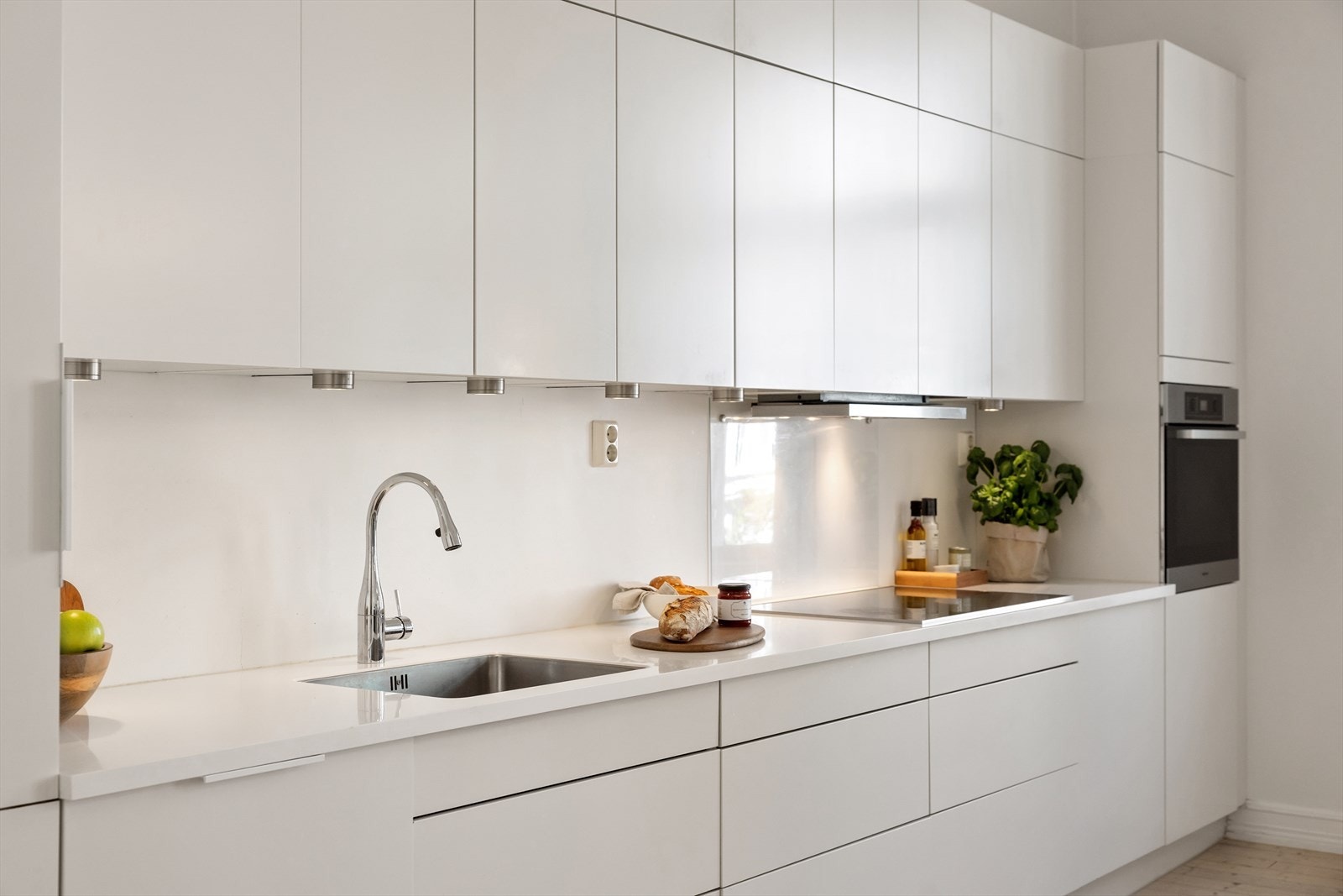 Kjøkkenet har moderne, slette fronter og en solid Corian benkeplate med integrert oppvaskkum og ettgreps blandebatteri. Galleribilde