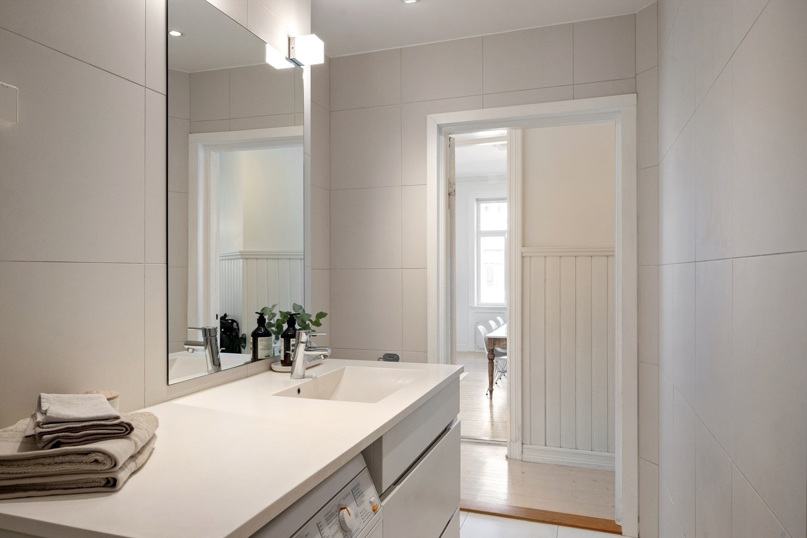 Badet er innredet med veggmontert toalett, servant med skap, speil og belysning. Galleribilde