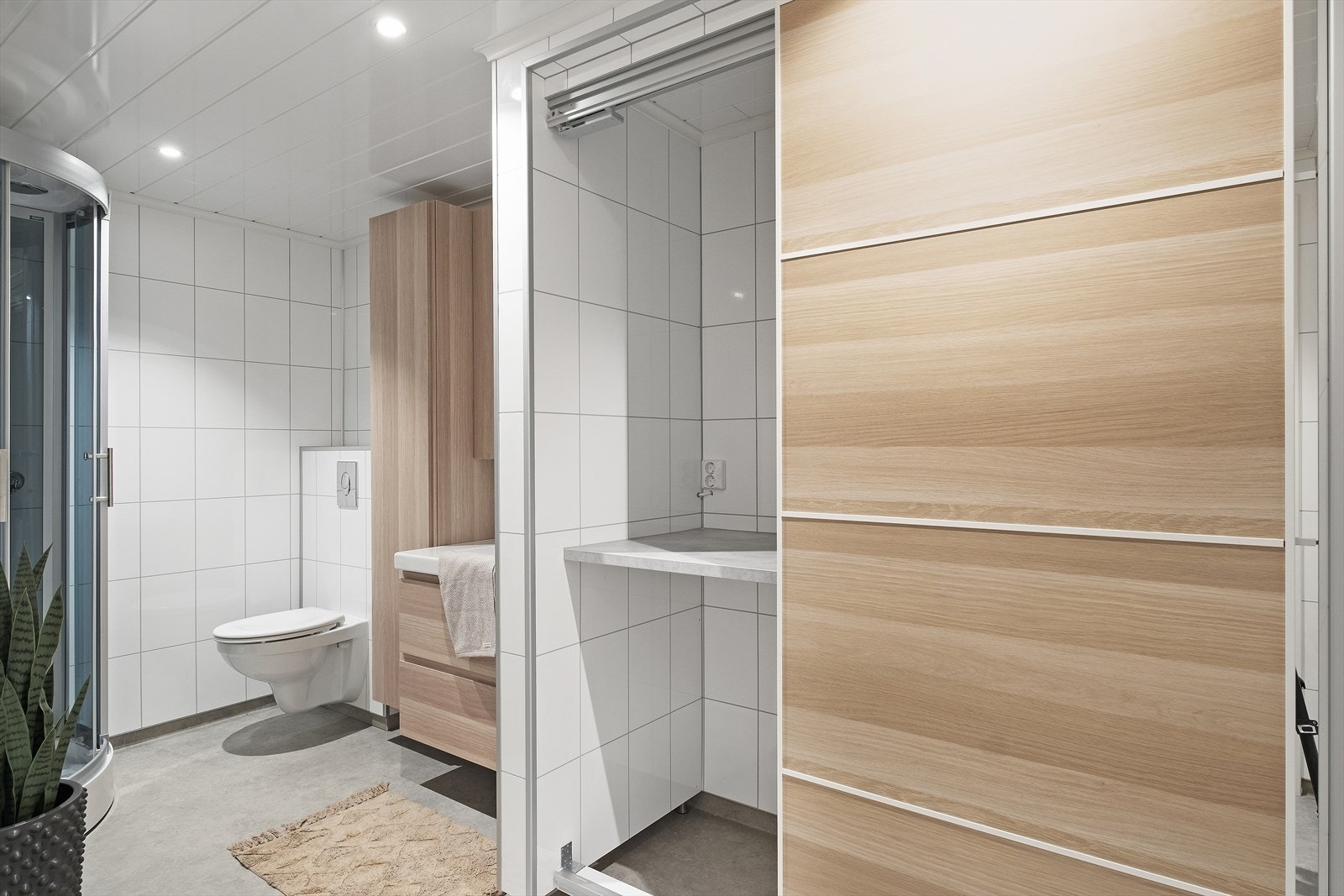 Praktisk bad med opplegg for vaskemaskin og utslagskum bak skyvedører. Galleribilde