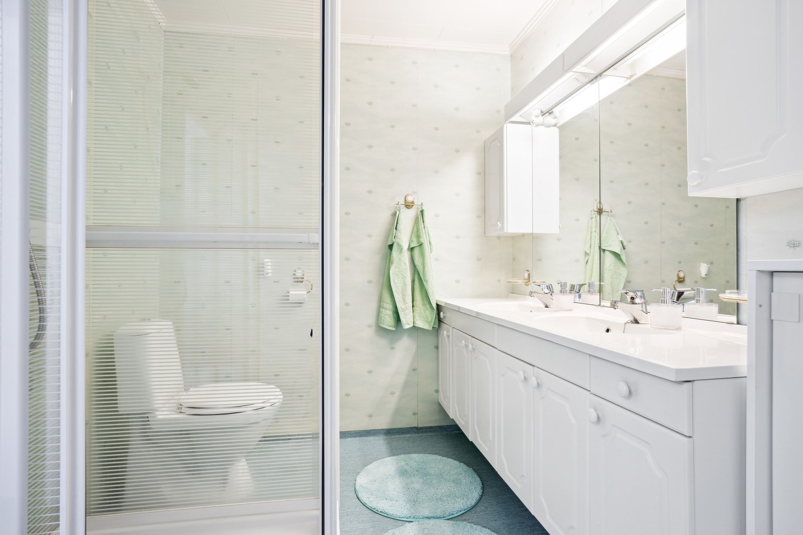 Badet er utstyrt med baderomsinnredning med dobbel servant, dusjkabinett og toalett Galleribilde