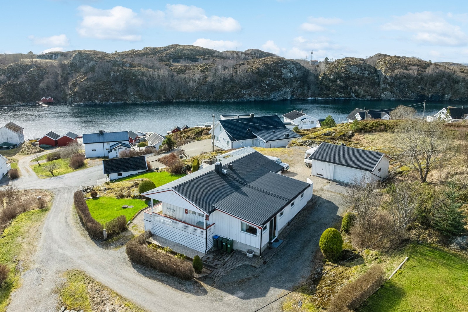 Eiendommen har en pent opparbeidet tomt med terrasser, parkeringsplasser og hage med plen og prydebusker Galleribilde