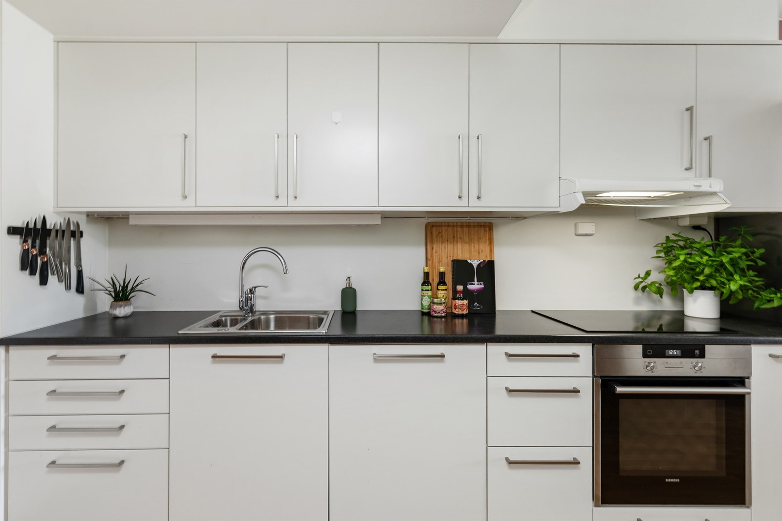 Kjøkken med integrert platetopp, komfyr og oppvaskmaskin Galleribilde