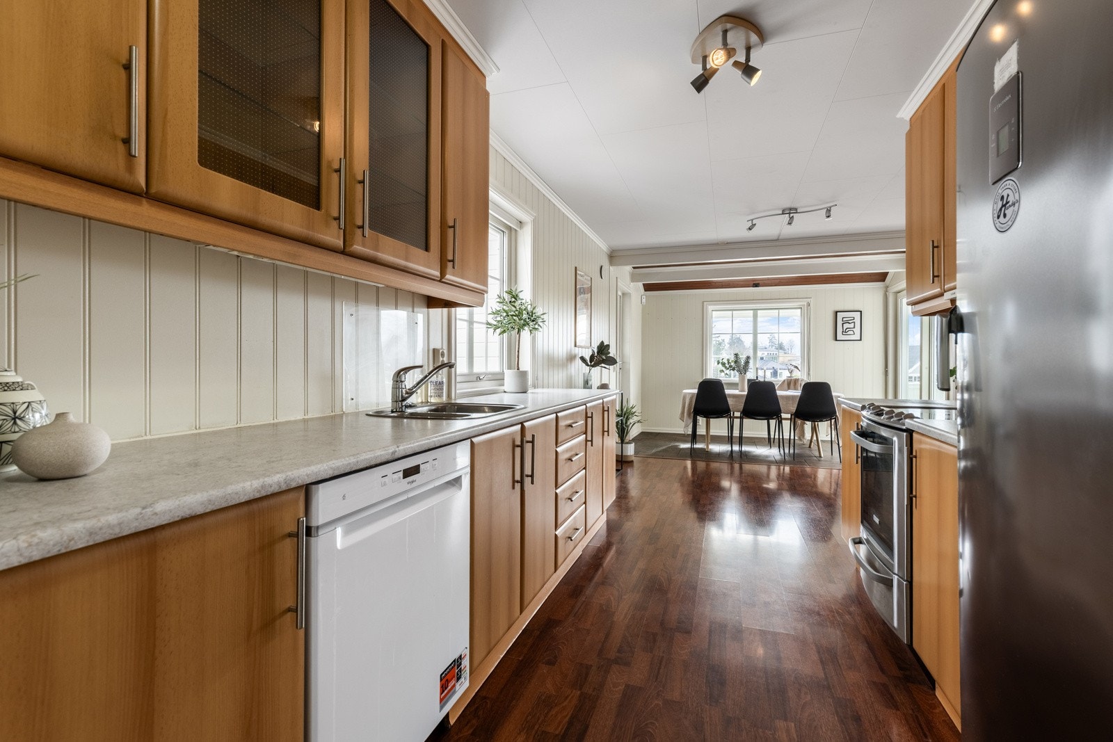 Innredningen har lyse, finerte fronter, vitrinedører, takhøye skap og lys laminatbenkeplate med nedfelt kum i stål. Galleribilde