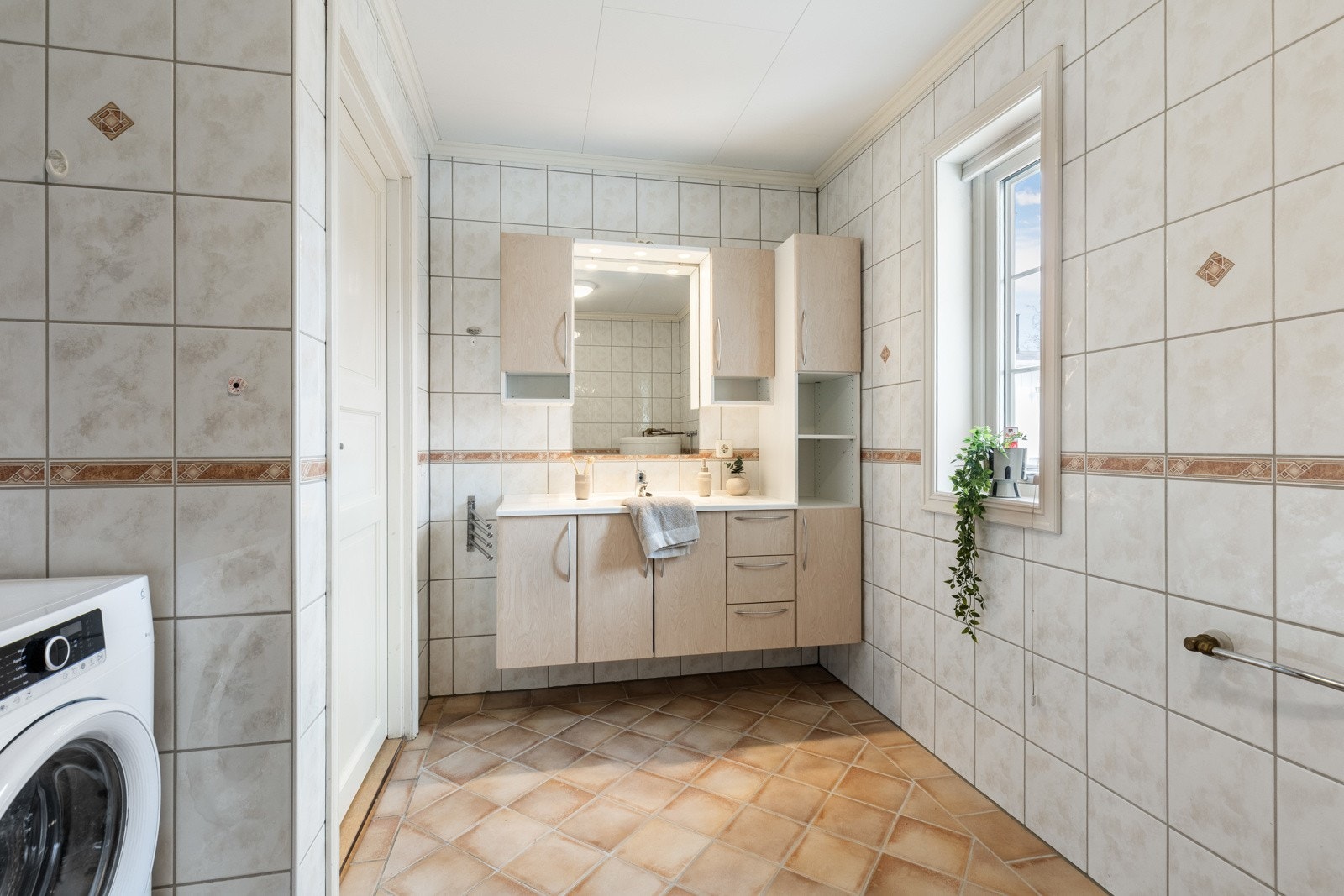 Boligen har et romslig og fint bad med lyse fliser på veggene og sandfargede fliser på gulv med gulvvarme. Galleribilde