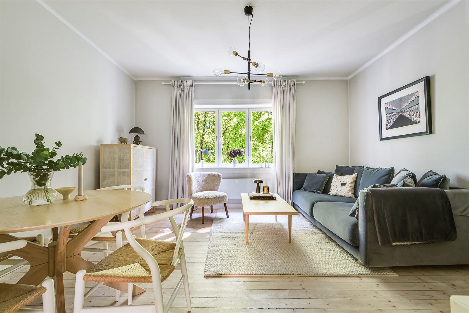 Stuen har store vindusflater som slipper inn rikelig med naturlig lys og gir en grønn utsikt mot trærne og parken. Galleribilde