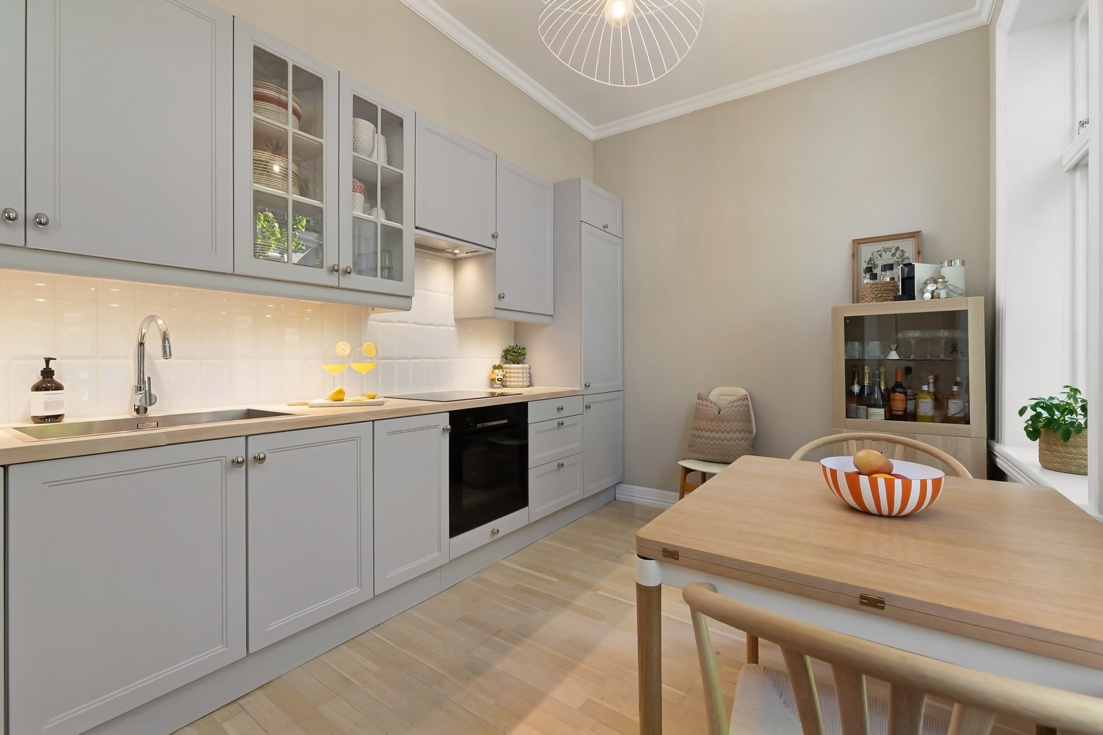 Delikat kjøkkeninnredning med profilerte fronter, benkeplate av tre og stor, nedfelt oppvaskkum av rustfritt stål Galleribilde