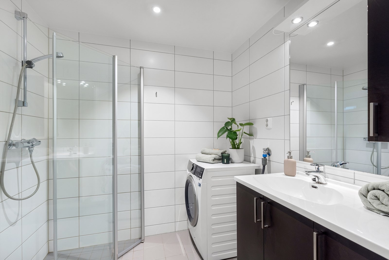 Et meget innbydende baderom med varmekabler i gulvet, servant, vegghengt toalett og dusj med svingbare dører i herdet glass. Galleribilde