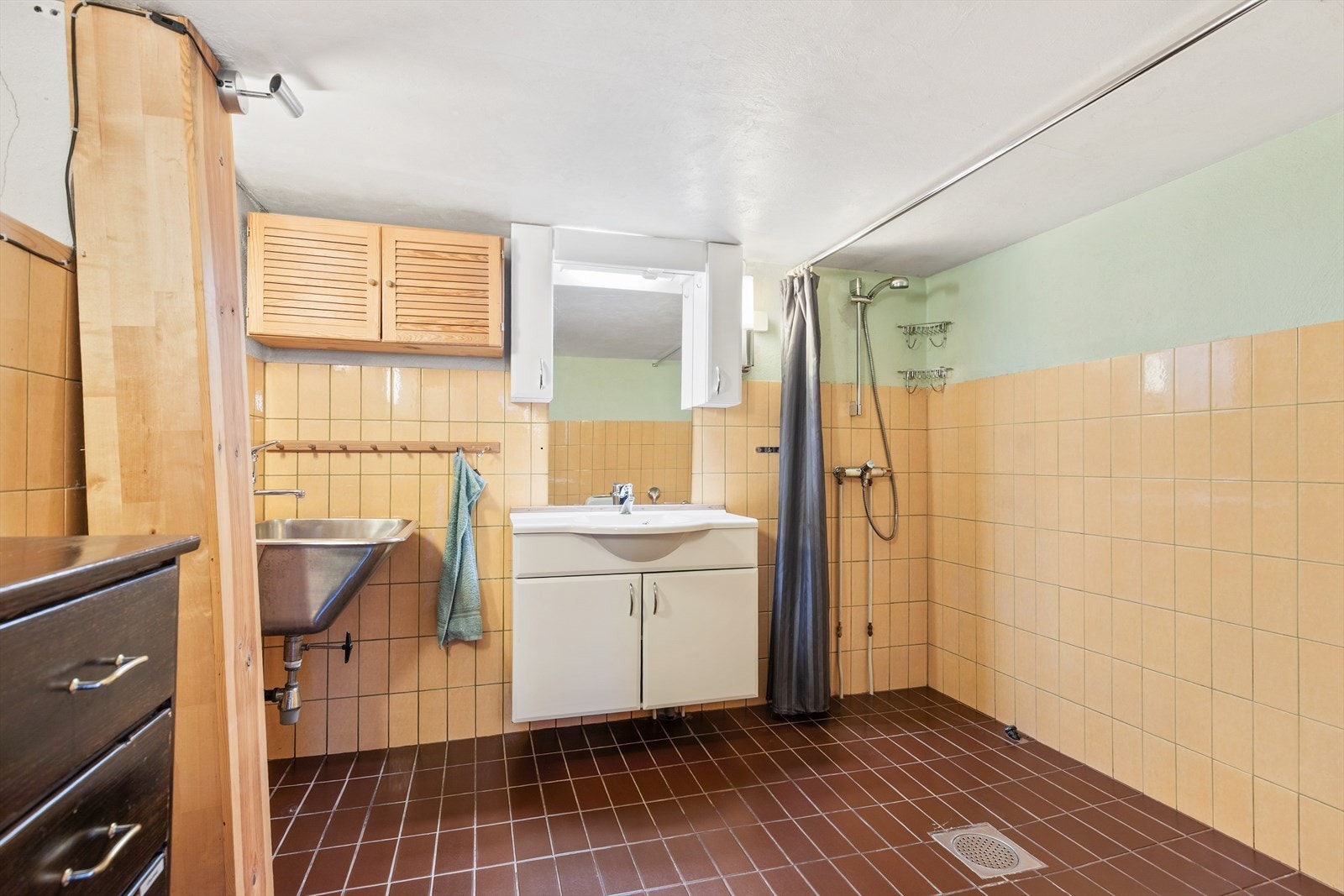 Bad med flislagt gulv og flislagte vegger. Badet er utstyrt med servant og dusjnisje. Speil og belysning i overkant av servant, samt utslagsvask. Galleribilde