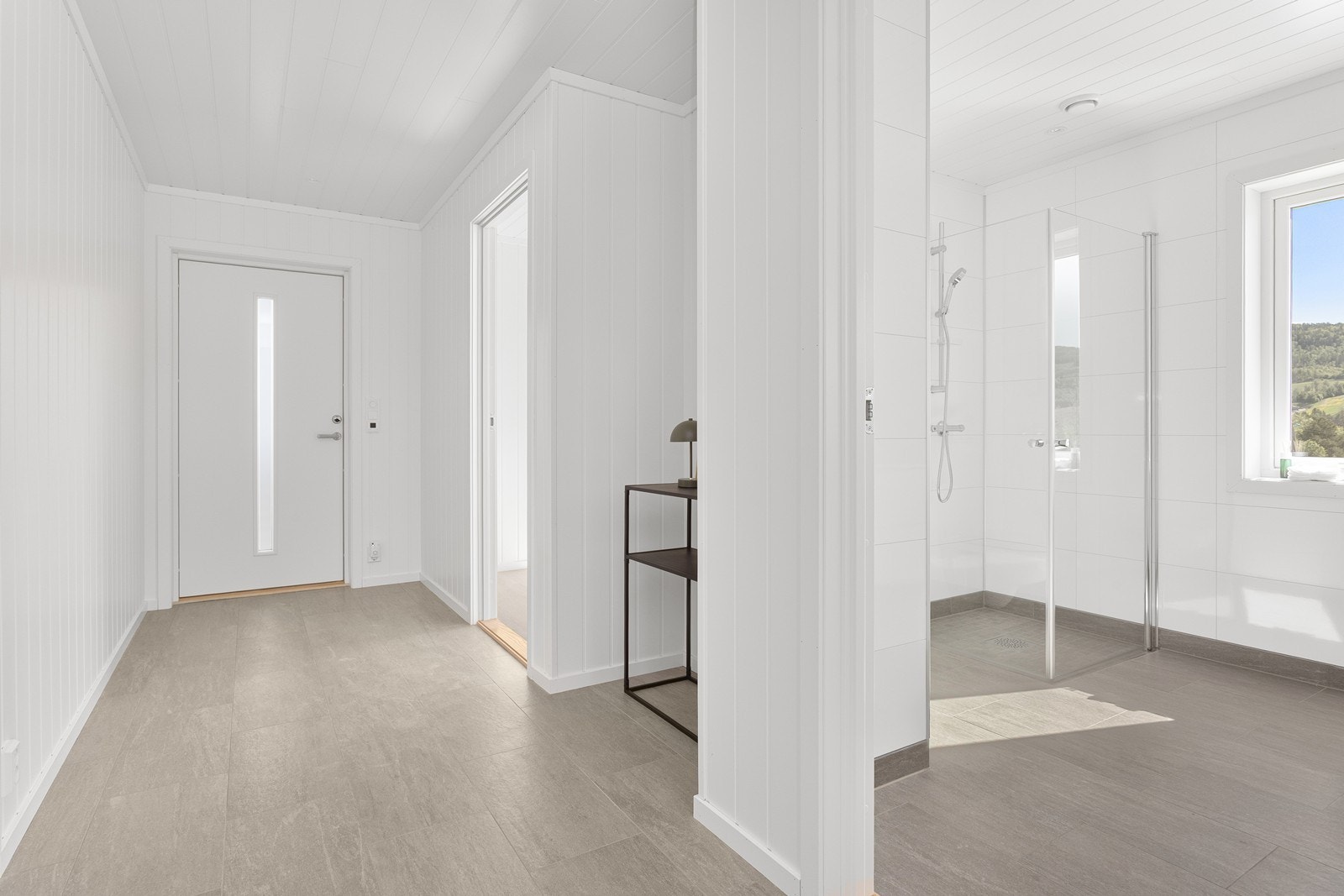 Det er brukt samme type gulvfliser i gang som på badet, noe som skaper en god flyt mellom rommene. Galleribilde