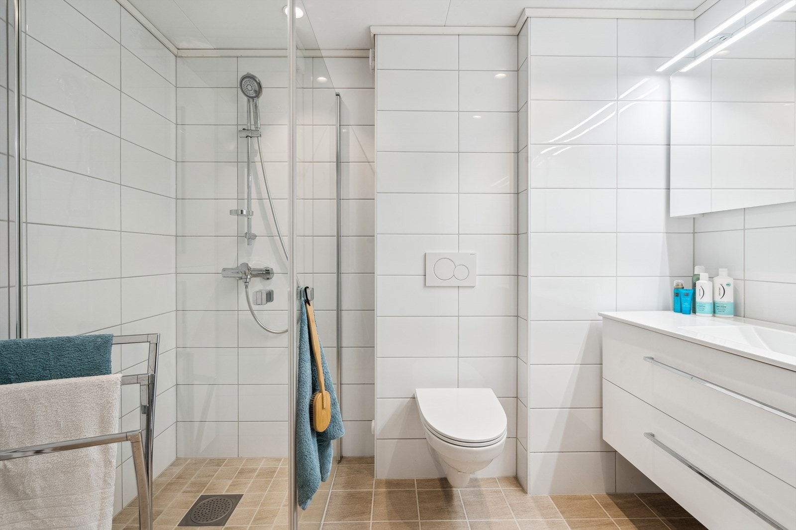 Pent helfliset bad som ble oppgradert i regi av borettslaget i 2020. Badet har servant med skapinnredning, overskap med speil fronter, et høyskap, vendbare dusjdører og vegghengt toalett Galleribilde