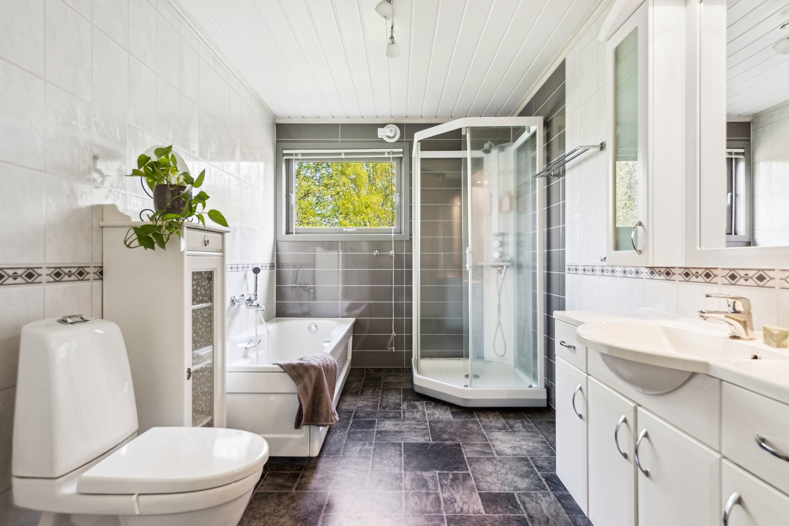 Stort bad fra 2011 med både badekar, dusjkabinett, innholdsrik innredning og toalett Galleribilde