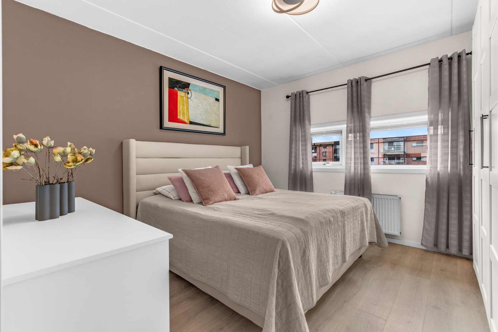 Romslig soverom innredet med dobbeltseng, kommode og garderobeskap langs den ene veggen. Galleribilde