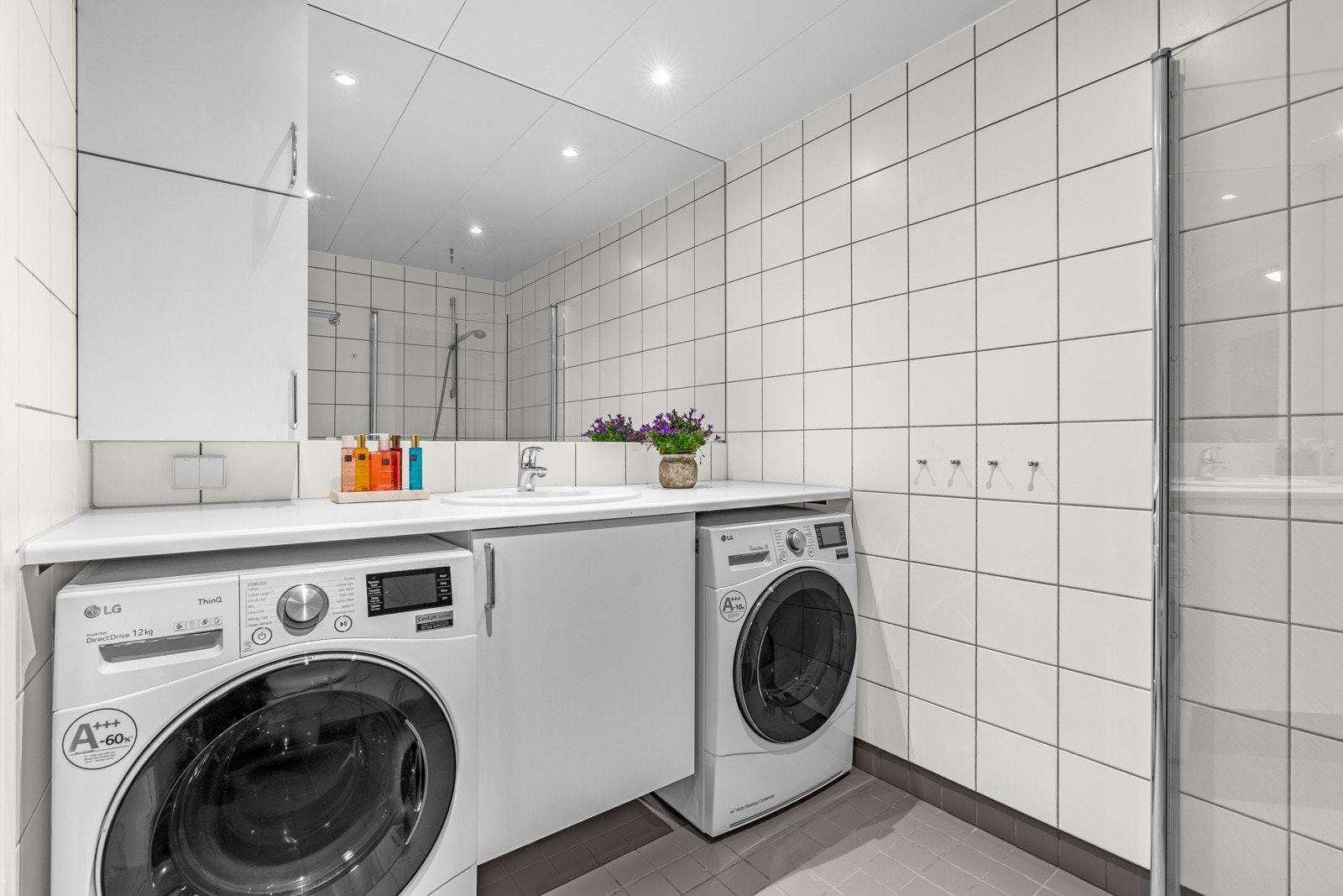 Effektiv plassløsning på hver side av vasken til vaskemaskin og tørketrommel. Galleribilde