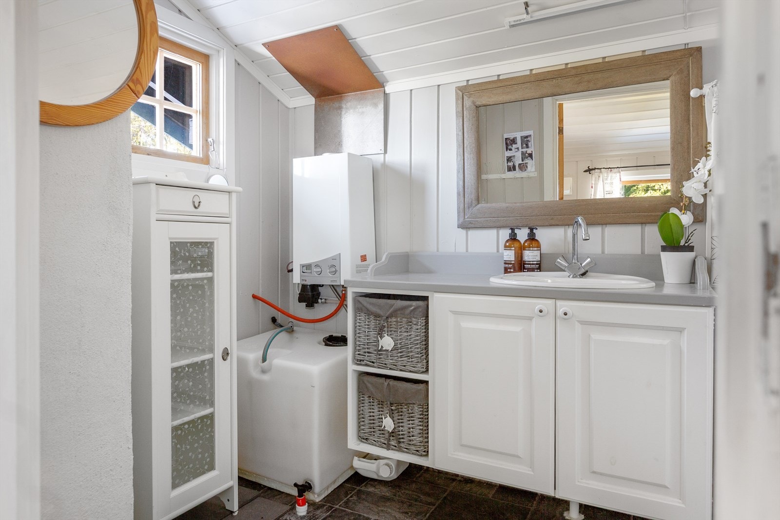 Hytta har et fint bad med lys baderomsinnredning og frittstående dusjkabinett. Badet har internt vannopplegg med vanntank på 140 liter, som fylles manuelt med vann fra borebrønn. Galleribilde