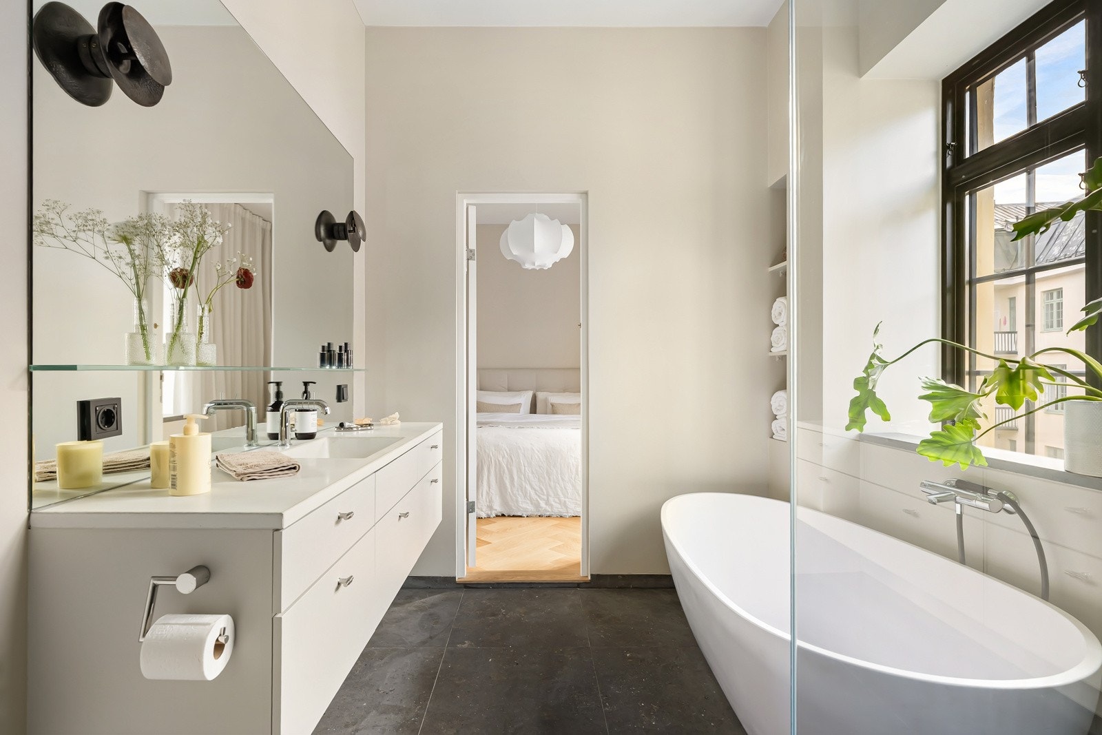 Romslig og lekker innredning med lyse skuffefronter og heldekkende servantbenk, samt et stort speil med innfelte bronsjelamper og glasshylle. Galleribilde