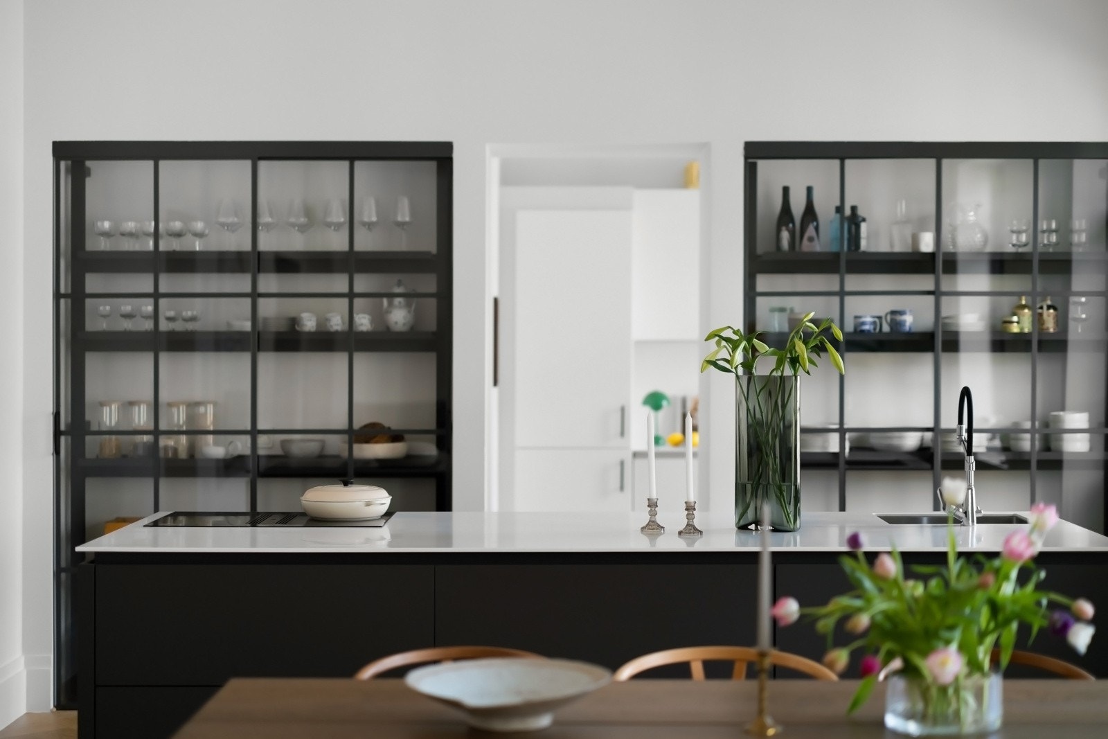 Høyskapene har skyvedører i glass med sorte metallsprosser, og det er plassert en sjenerøs kjøkkenøy i skillet mot stuen. Galleribilde