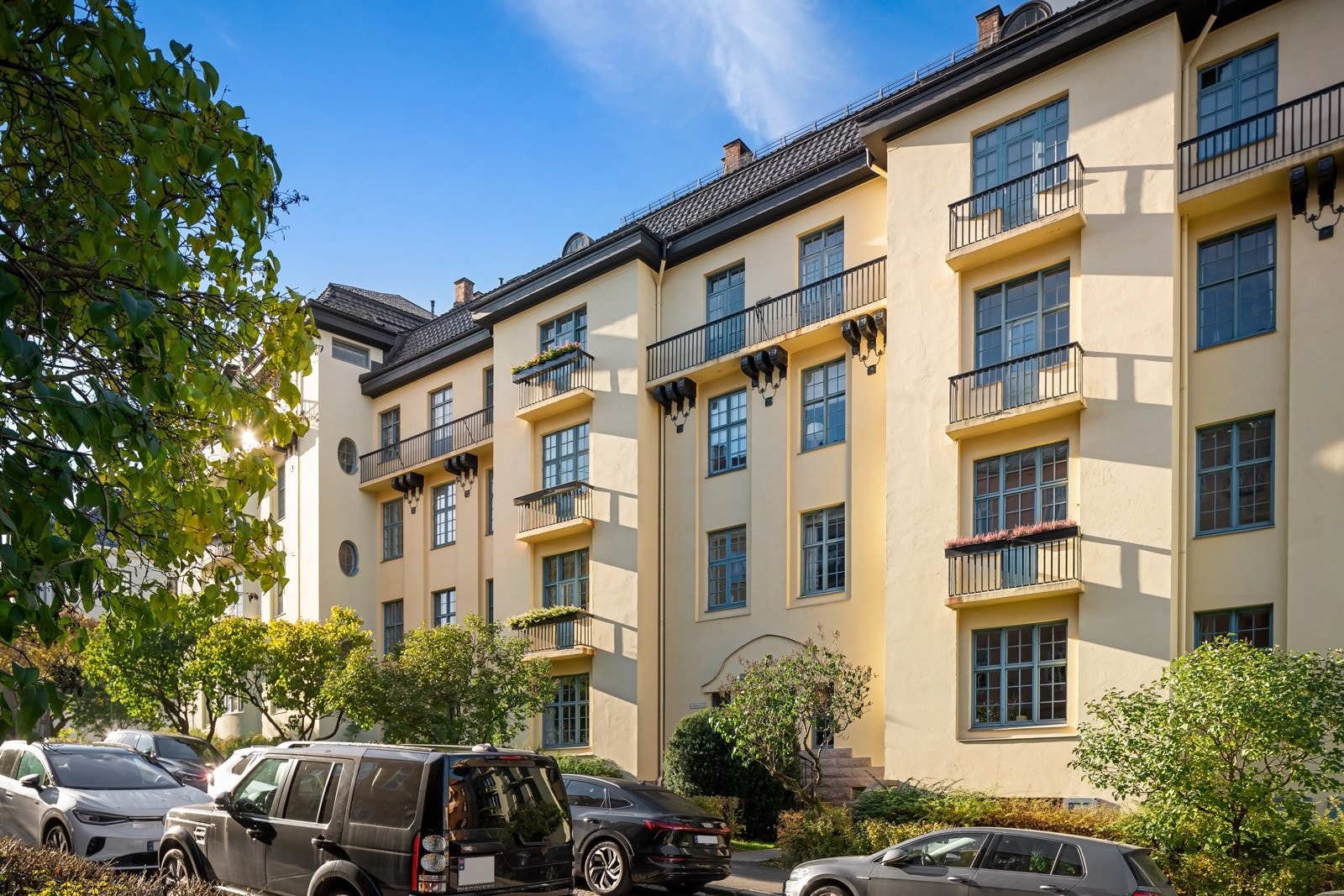 Mot gaten er det etablert en bred forhage med plen, hekk, trær og lubne, vintergrønne prydbusker. Galleribilde