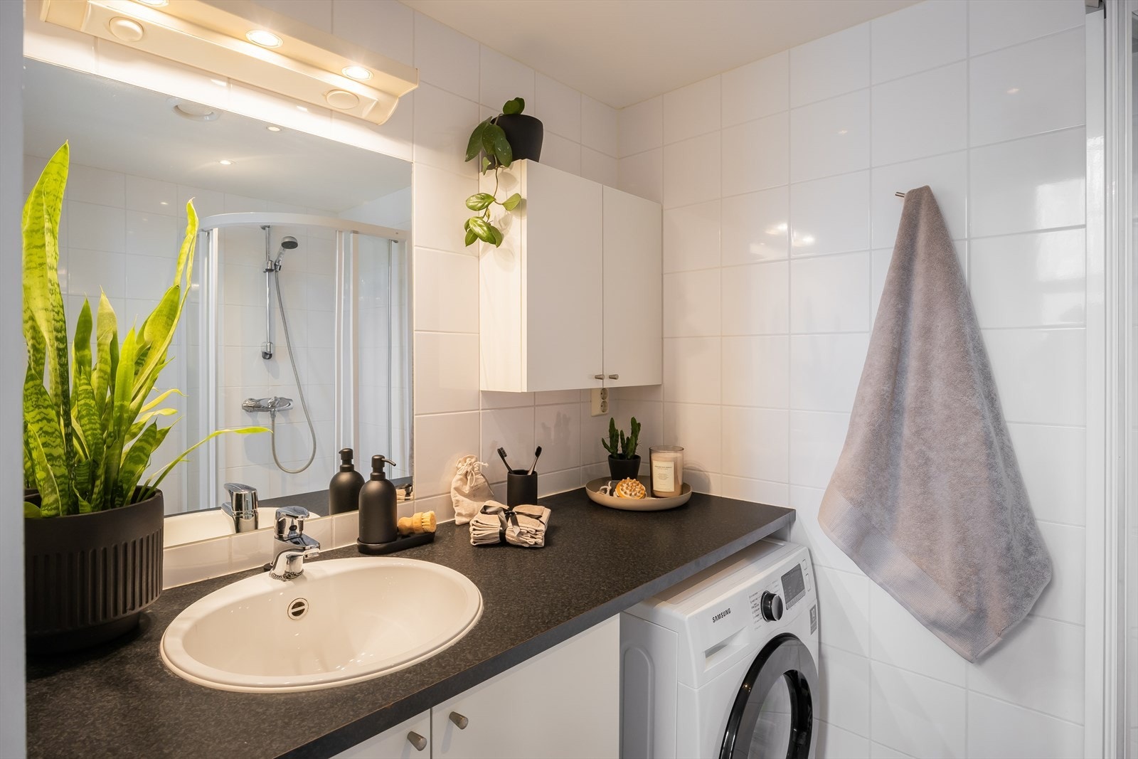 Flislagt bad med plassbygd benkeplate, opplegg for vaskemaskin, vegghengt toalett og varme i gulv. Galleribilde