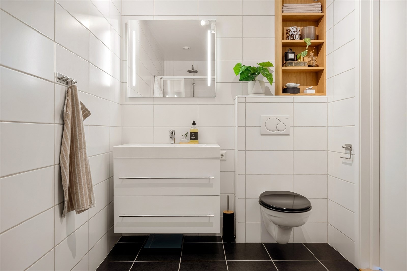 Badet har gulvfliser med varmekabler, veggfliser og malte plater i taket. Galleribilde
