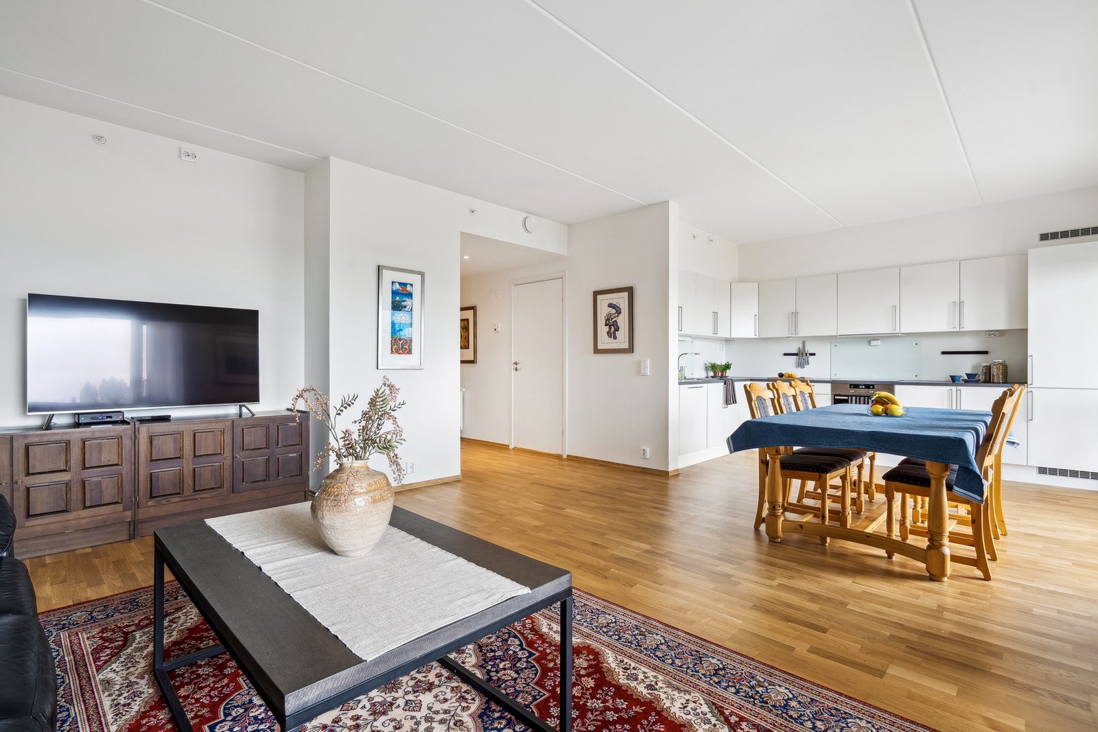 I overgangen mellom stue og kjøkkensone er det god plass til spisebord - en praktisk og naturlig plassering Galleribilde