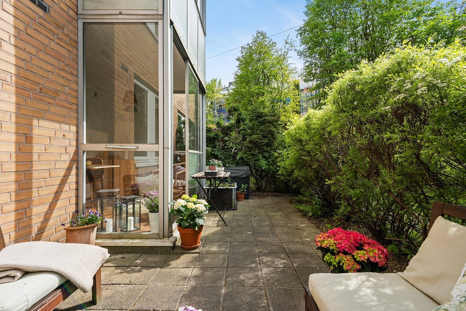 Hyggelig, skjermet uteplass. På andre siden av hekken er borettslagets felleshage som er avskjermet fra gaten med gjerde/port Galleribilde