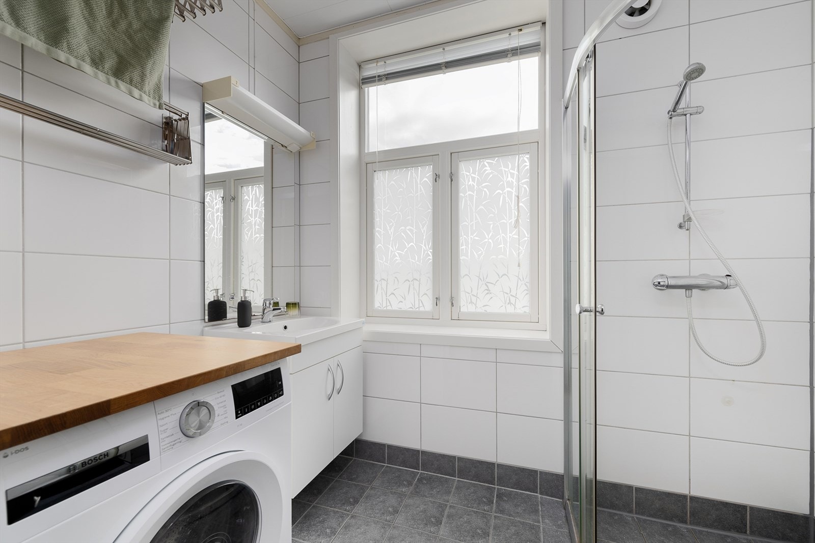 Flislagt baderom har gulvvarme og opplegg for vaskemaskin Galleribilde