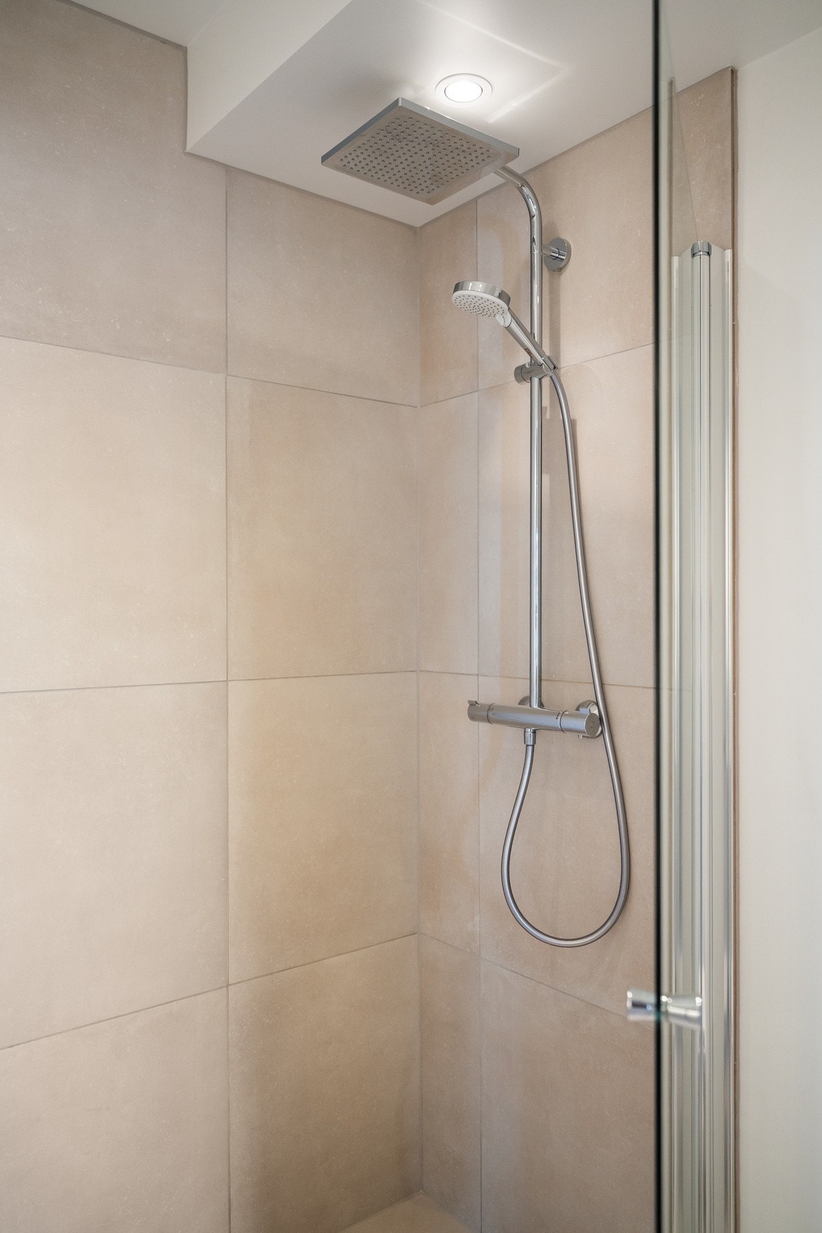 Dusjhjørne med dusjvegg i herdet glass og pen dusjgarnityr med regnfallsdusj og hånddusj. Galleribilde