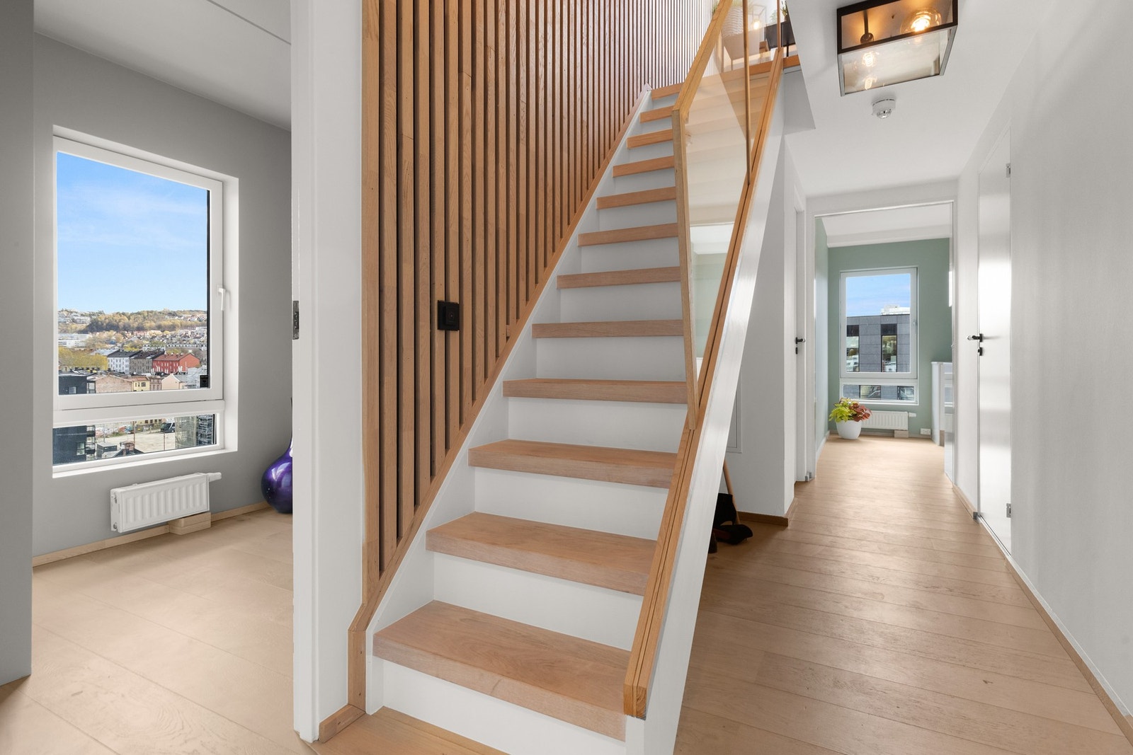 Innbydende gang/trapperom med glassrekkverk og hvitpigmenterte eikespiler. Galleribilde