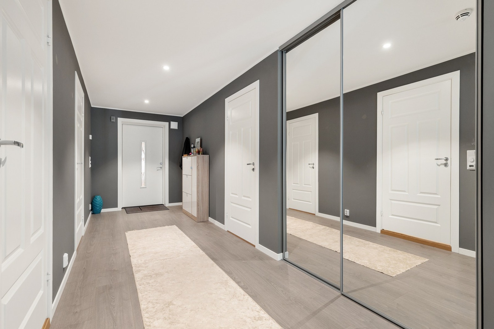 Det er montert en praktisk skyvedørsgarderobe med speilfronter for oppbevaring av yttertøy og sko Galleribilde