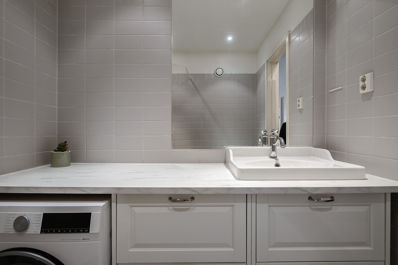 Badet har opplegg for vaskemaskin, og en praktisk benkeplate fra vegg til vegg. Galleribilde