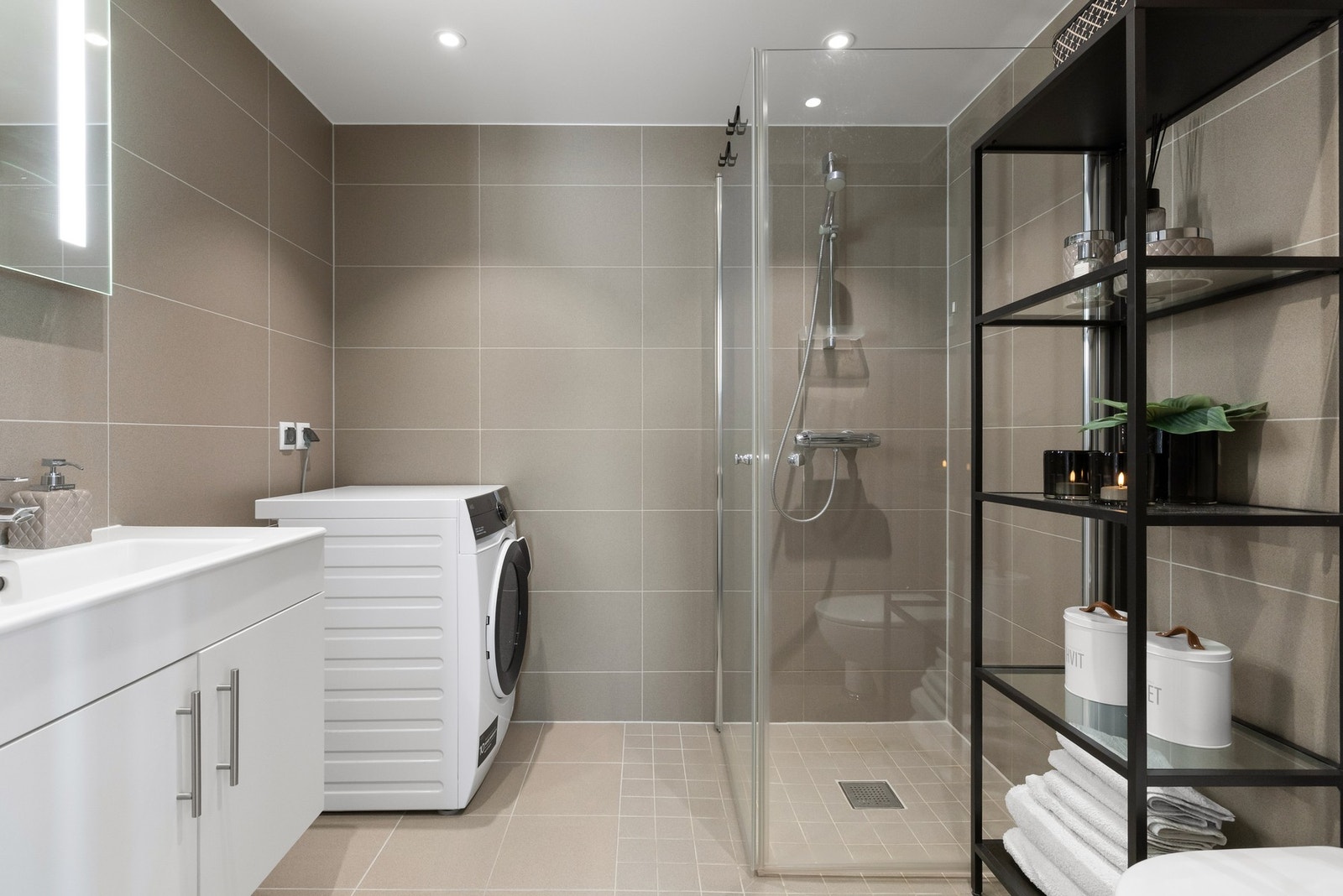 Romslig baderom med varmekabler, moderne materialvalg og opplegg for vaskemaskin. Galleribilde